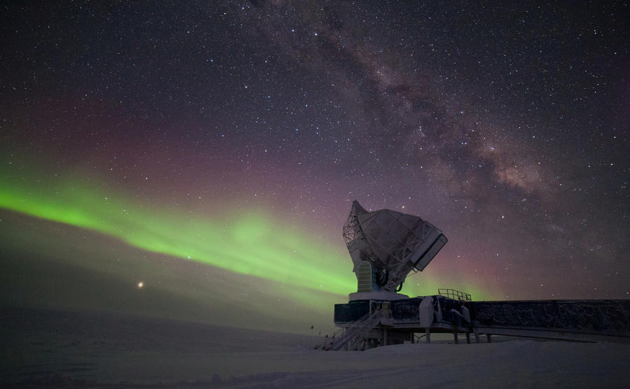 The South Pole Telescope illuminated by aurora australis and the Milky Way. Jupiter is brightly visible on the lower left, Saturn is located to the right of the telescope. The outside temperature is -60°C.