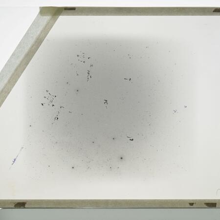 Glass plate AI32380 measures 8 inches by 10 inches. This glass plate is a negative, meaning the image is a reverse of the night sky. Markings on the glass track the comet's trajectory.