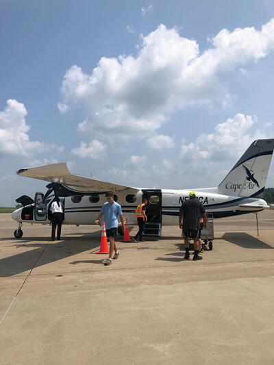 Nine-seater crop duster plane on the tarmac with a few people standing around