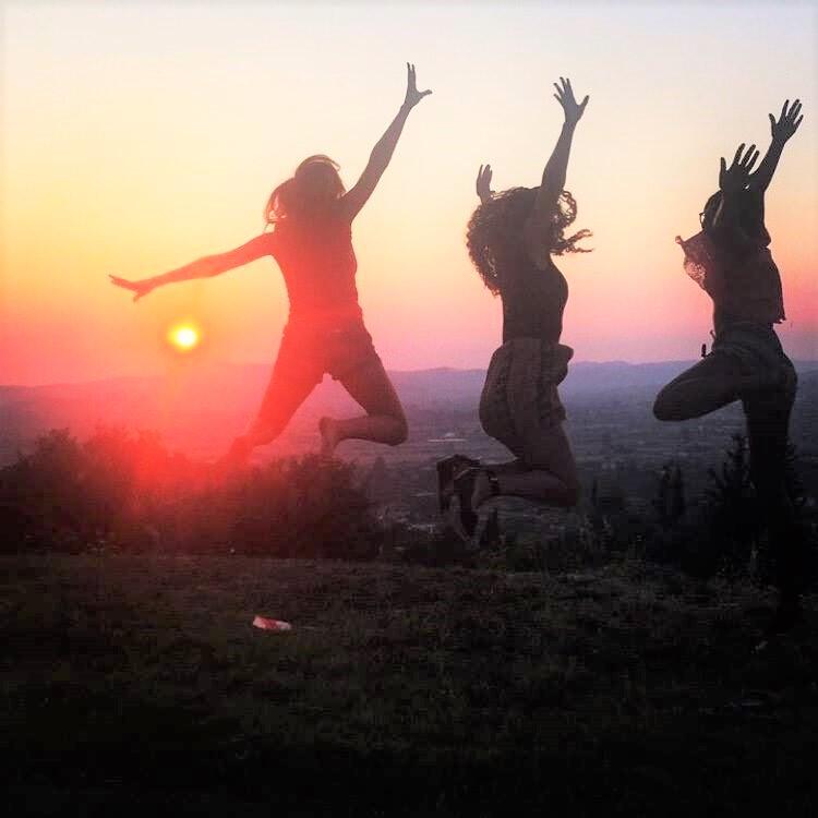 Τhree female students οf the Harvard Summer School Program in Greece 2015 jumping happily at the sunset view in Olympia.