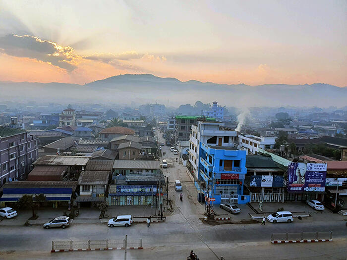 View overlooking the buildings of Lashio in Myanmar, with the sun setting in the background behind the mountains