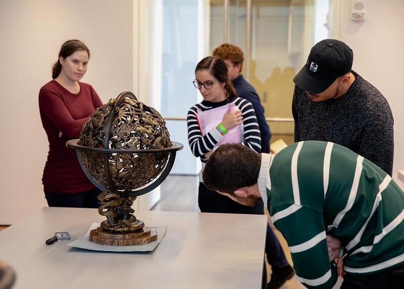 Students in a Bok Seminar observe a bronze sculpture on a table at the Art Museum