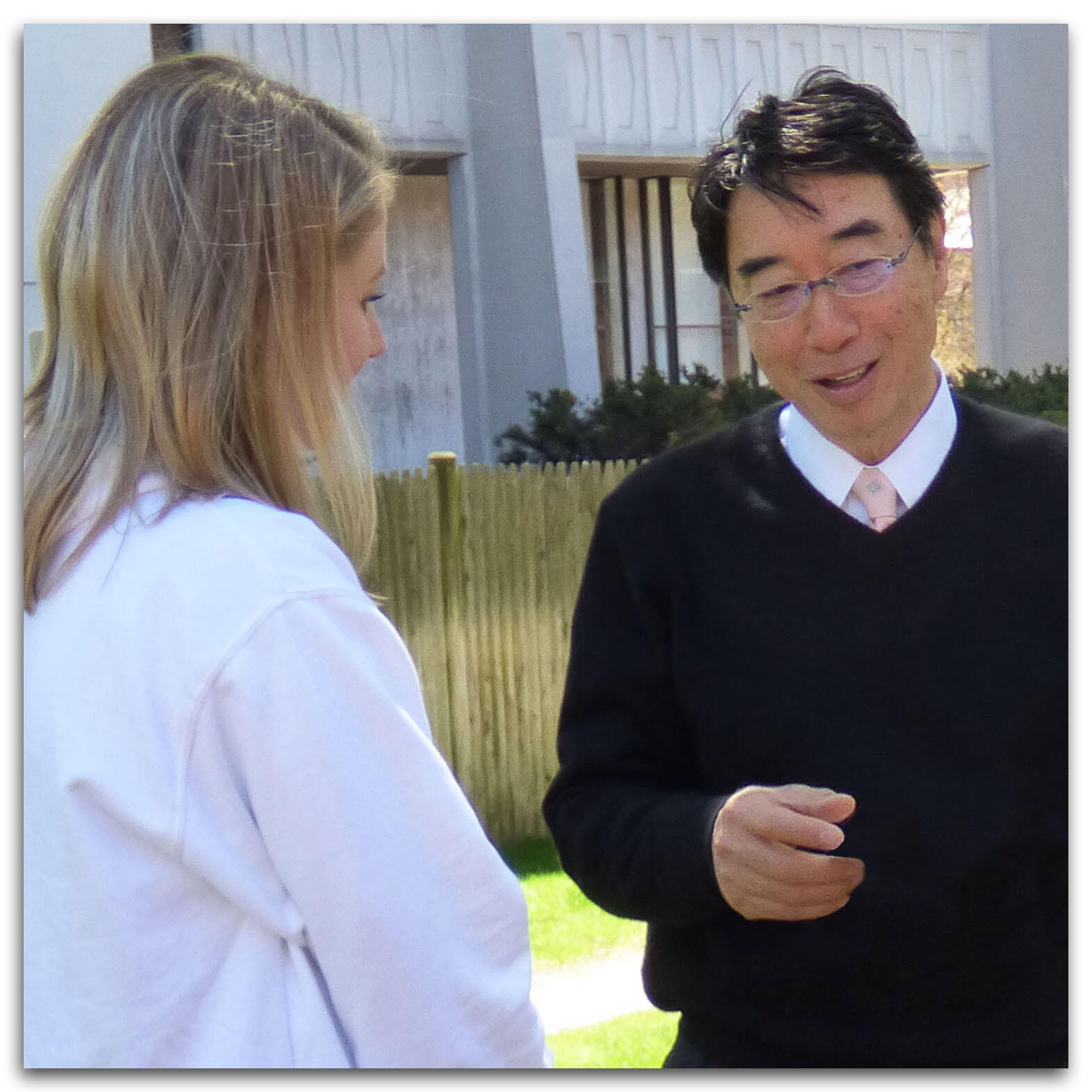 Professor Ryuichi Abe, right, speaks to blond student seen from behind, left