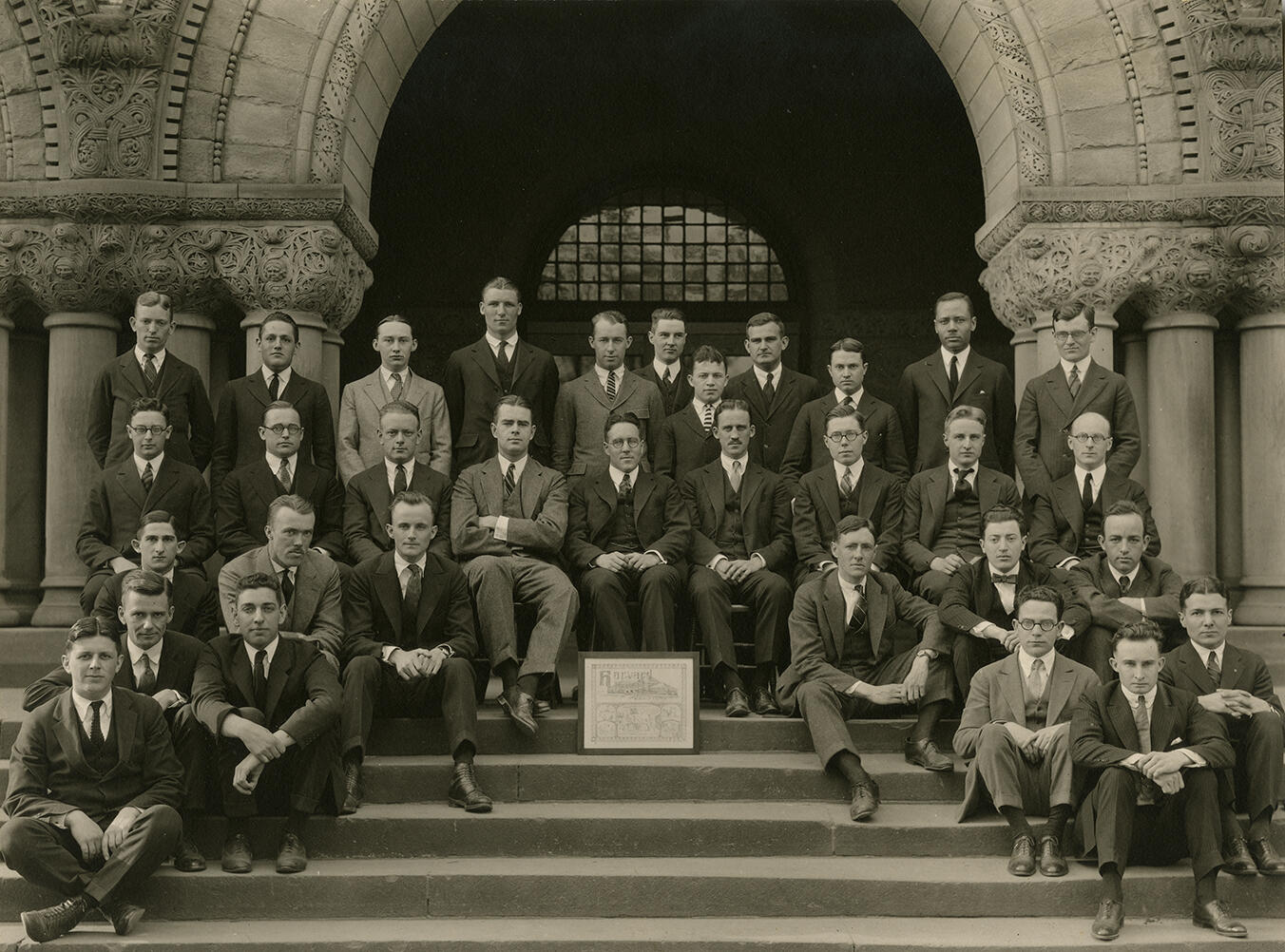 Thirty-two male members of the Harvard Law Review Board of Editors sitting and standing in front of Austin Hall