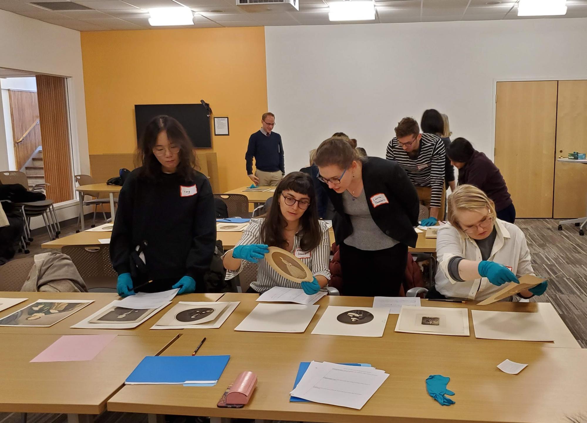Students gathered around a table looking at salted paper prints.