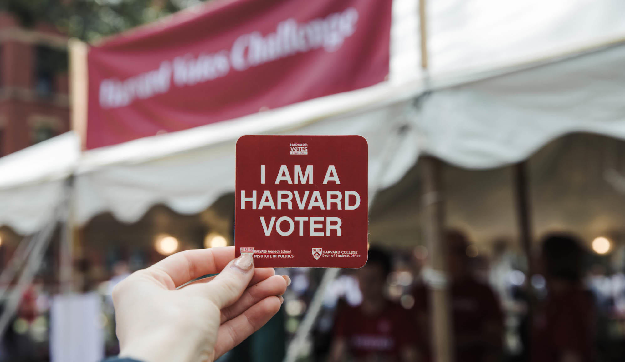 Person holds an "I am a Harvard Voter Sticker"
