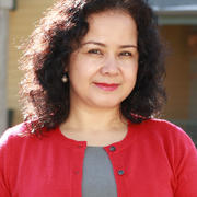 From the shoulders up, Gulnar Eziz smiles at the camera, wearing a red cardigan