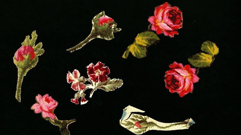 Seven cloth flowers on a black background.