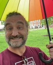 a middle aged man holding a rainbow umbrella